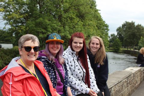 women sat on wall smiling