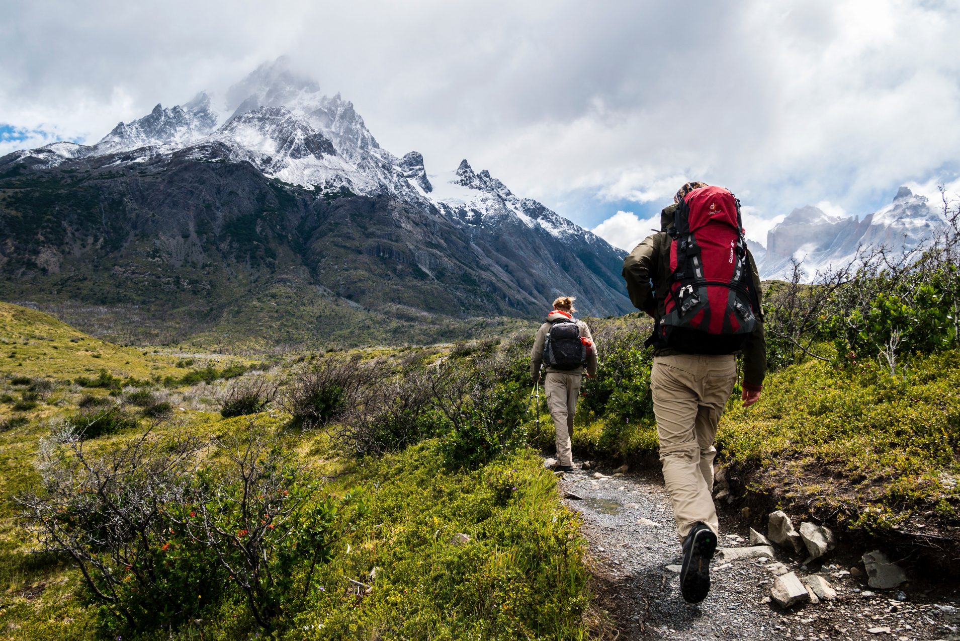 man and woman hiking towards mountain with backpacks