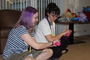 young women sat cross-legged learning a cup song routine