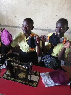 Ugandan young women holding up handmade sanitary towels from FIZZ mission trip