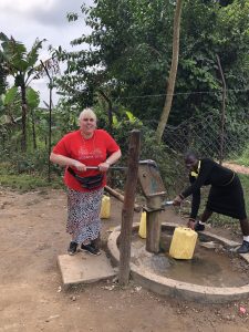 Girls' Brigade volunteer and Ugandan girl working at a water pump on FIZZ mission trip