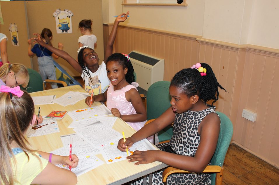 girls colouring in sat at a table