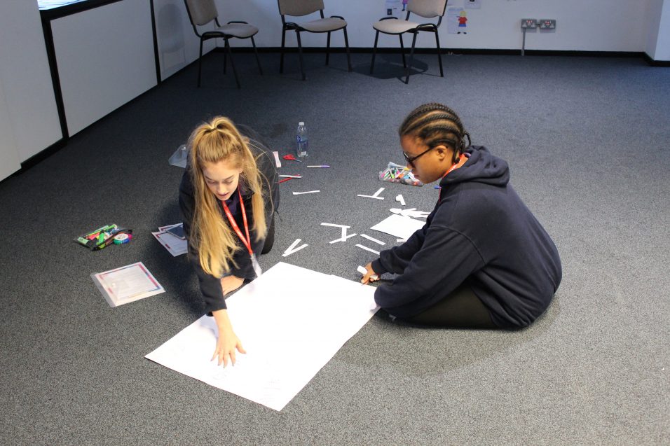 Girls' Brigade young leaders creating poster on floor