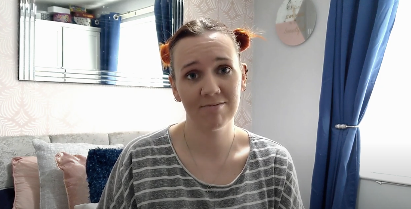 Young woman sat in bedroom talking to camera