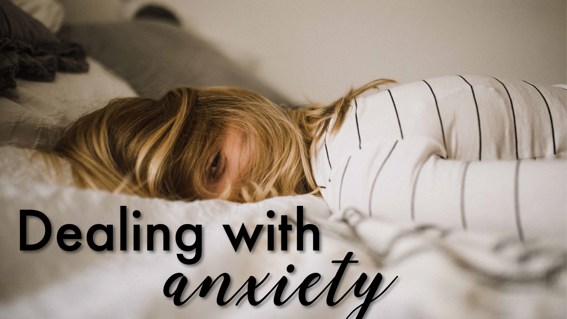 Girl laid on a bed peering through her hair