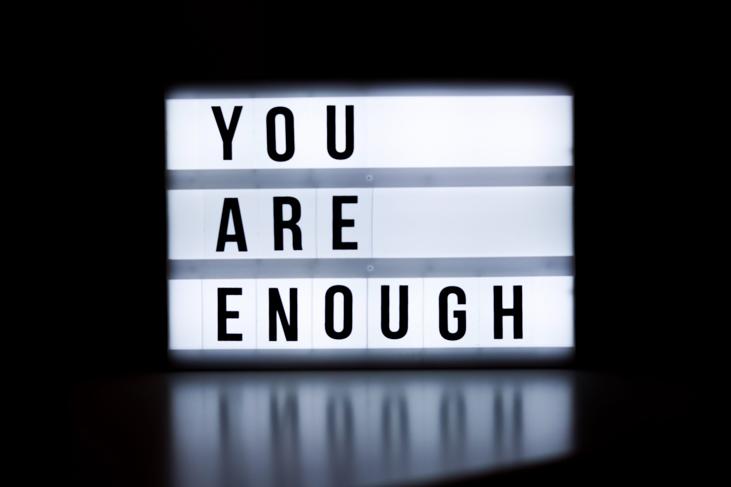 The words 'You are enough' displayed on a sign