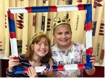 GB members posing behind frame wearing crowns