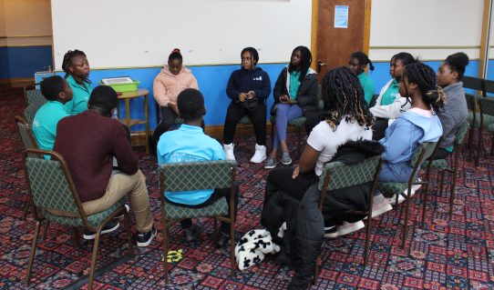 GB members sat in a circle listening to GB leader speak