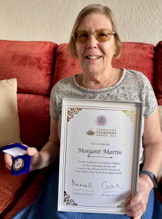 Margaret Martin holding Coronation Champions Award certificate and medal