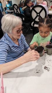 GB member and woman planting seeds together