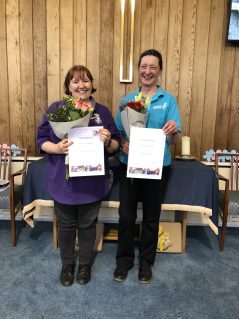 Two GB leaders holding flowers and service award certificates