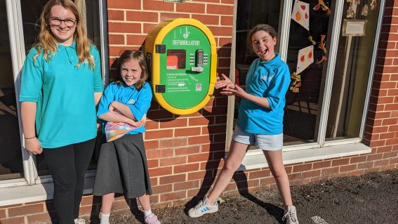 GB members standing with defibrillator