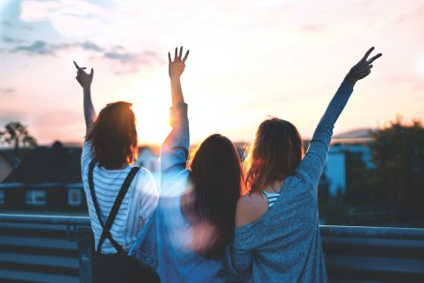 Three girls with arms in the air