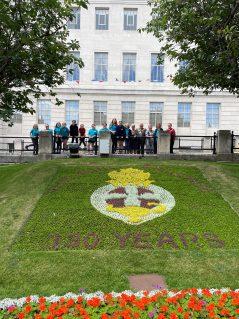 GB members and volunteers gathered around GB crest flower display