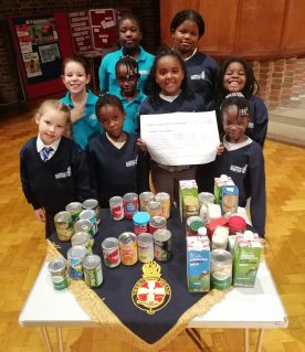 GB members posing behind a table of tinned and boxed food items that have been donated