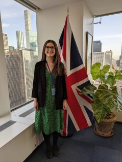 Hannah at UN CSW beside a Union Jack flag