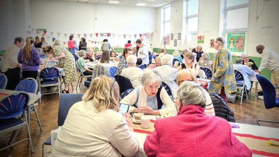 Room of women and girls enjoying afternoon tea.